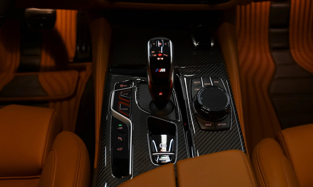 BMW F90 M5 center console with installed gloss carbon trims and light brown leather