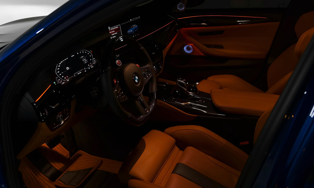 Blue BMW F90 M5 interior through the driver's door, with light brown leather and carbon trims