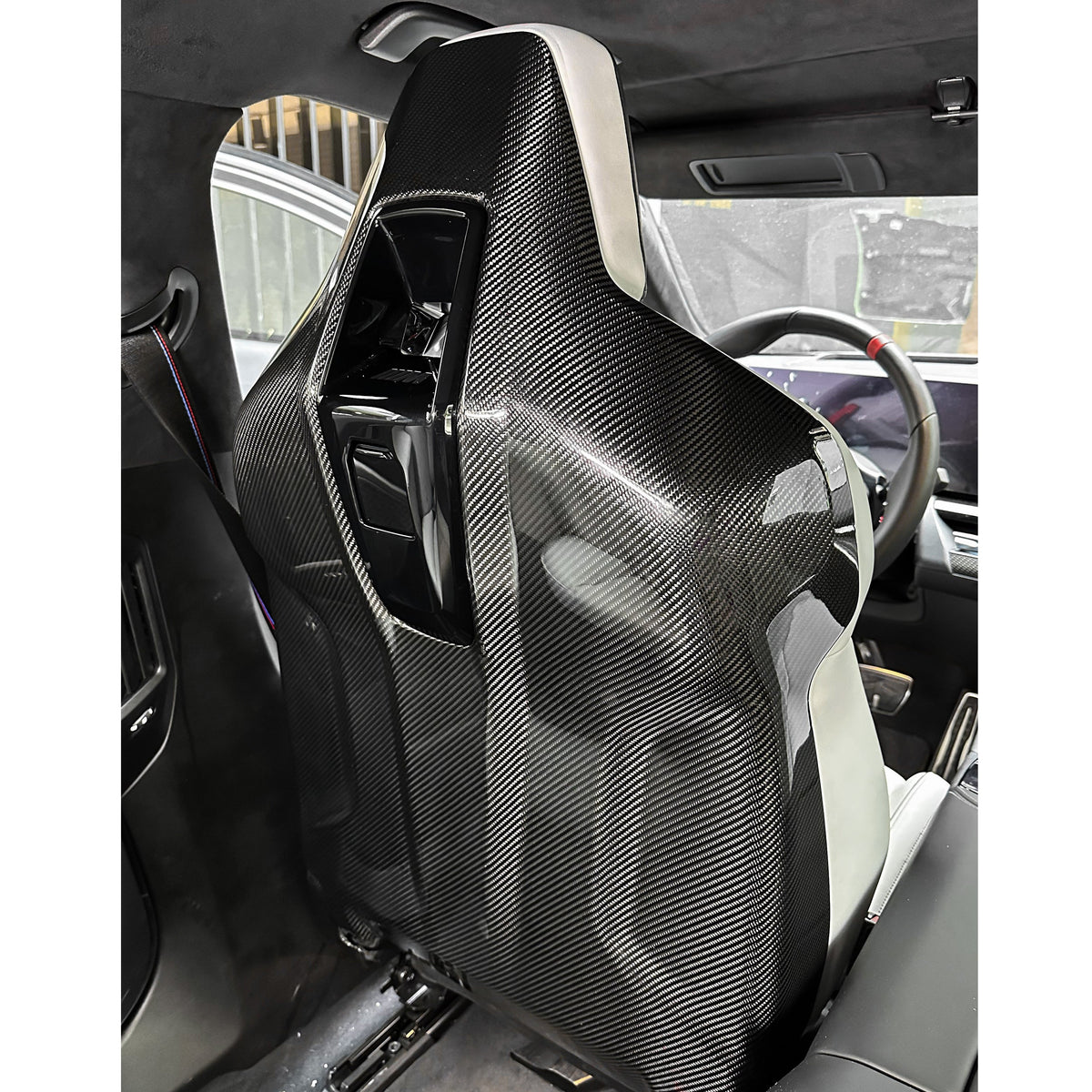 Carbon seat back cover on the front seat from behind, in a gray interior – BMW G90 M5
