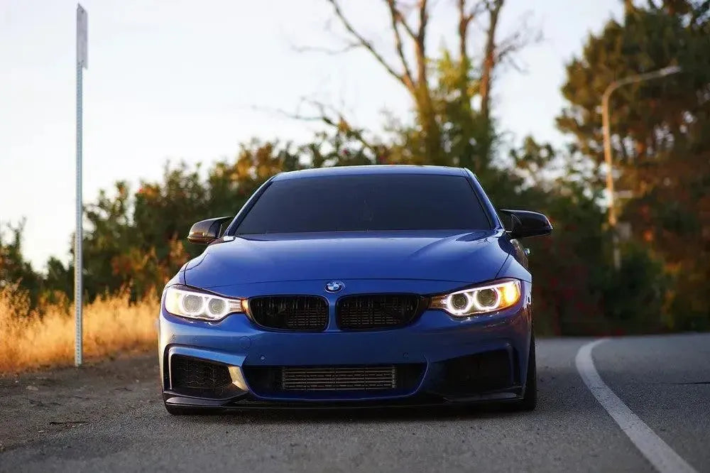 Kék BMW 4-es sorozat szemből az úton, fényes fekete M Style tükörborítással