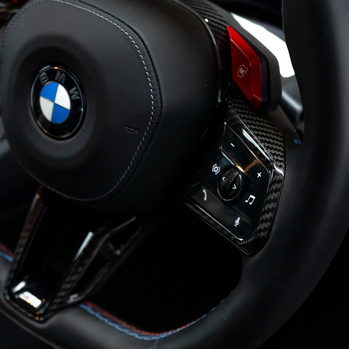 Kormány bal küllőjének gombjai, carbon díszítés és piros váltófül közelről (M5 Style) – BMW F széria