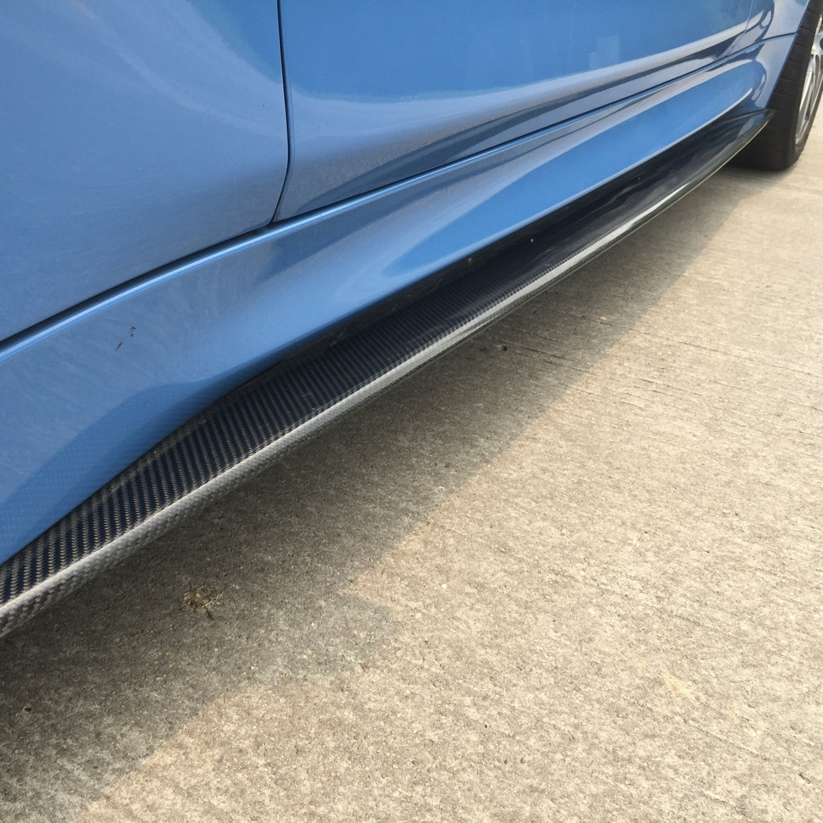 Carbon side skirt of a blue BMW M3/M4 from a low angle, along the side sill (MP Style)