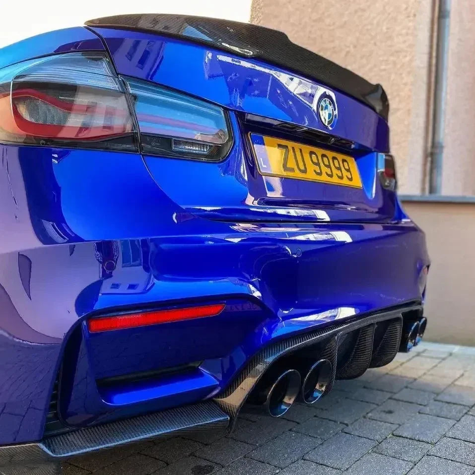 Kék BMW F80 M3 hátulja alacsonyról, ferdén és közelről, carbon csomagtartó spoilerrel (M4 Style)