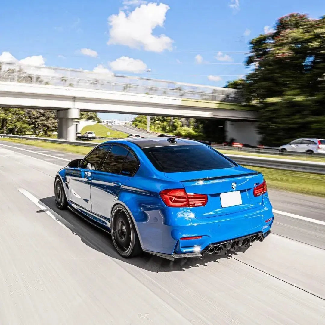 Kék BMW F80 M3 autópályán haladva, ferdén hátulról, carbon spoilerrel (MP Style)