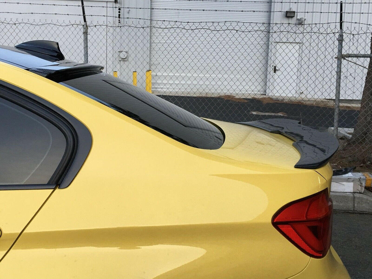 Sárga BMW F80 M3 hátsó ferde nézetben, carbon hátsó szélvédő spoilerrel (AC Style) és csomagtartó spoilerrel
