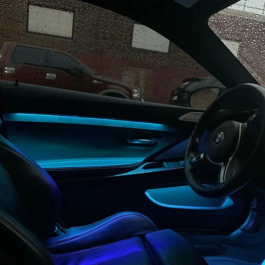 Kék ambient hangulatvilágítás BMW F82 M4 utasterében, nyitott ajtón át nézve
