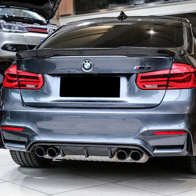Gray BMW F80 M3 rear in a showroom, with carbon diffuser and trunk spoiler (MP Style)