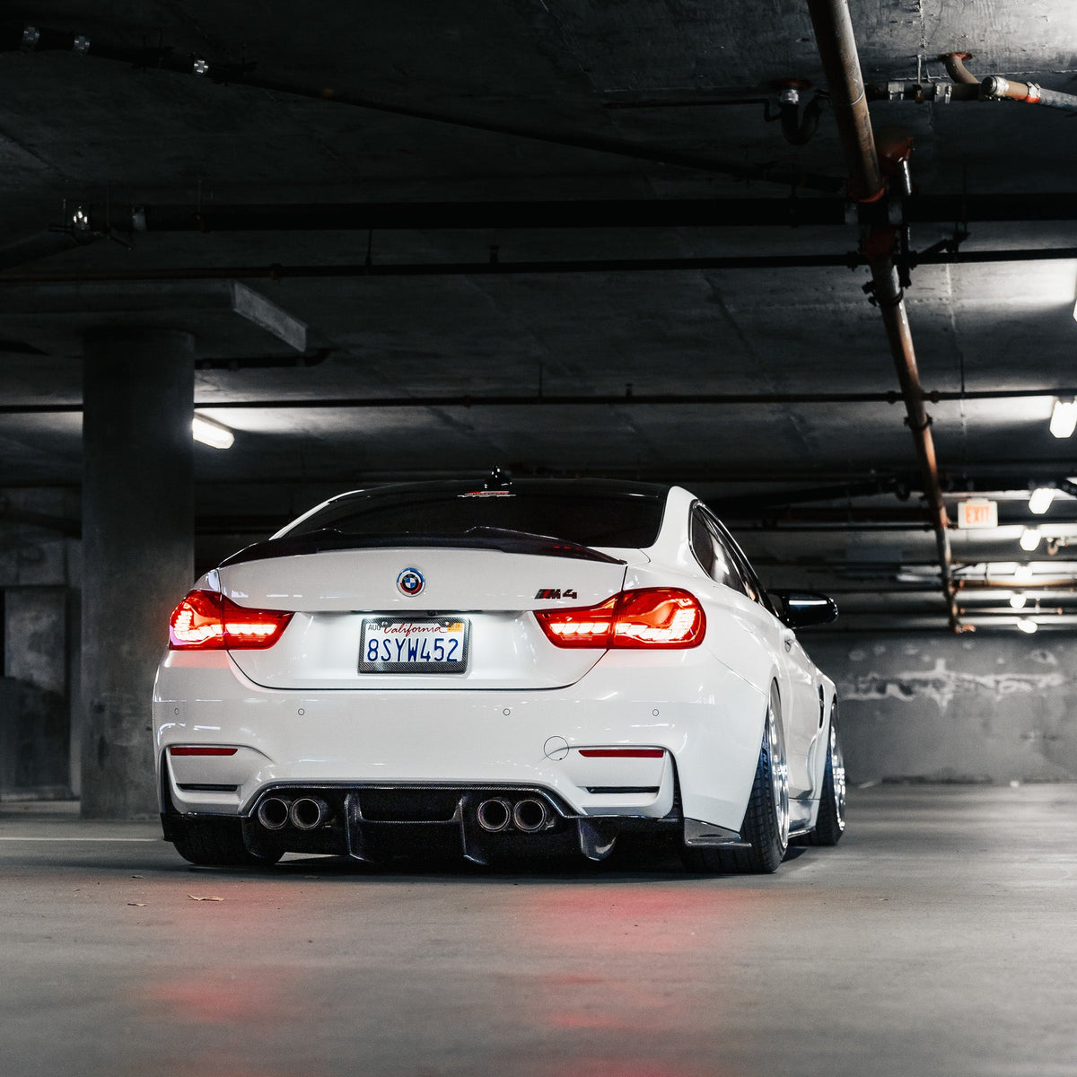 Fehér BMW F82 M4 hátulnézetből a parkolóházban, carbon diffúzorral (PSM Style)
