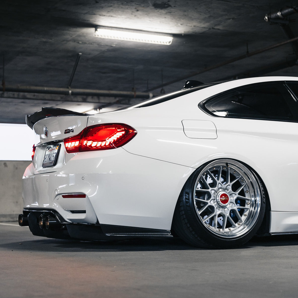 Carbon hátsó diffúzor (PSM Style) fehér BMW F82 M4-en, ferde oldal-hátulnézet garázsban