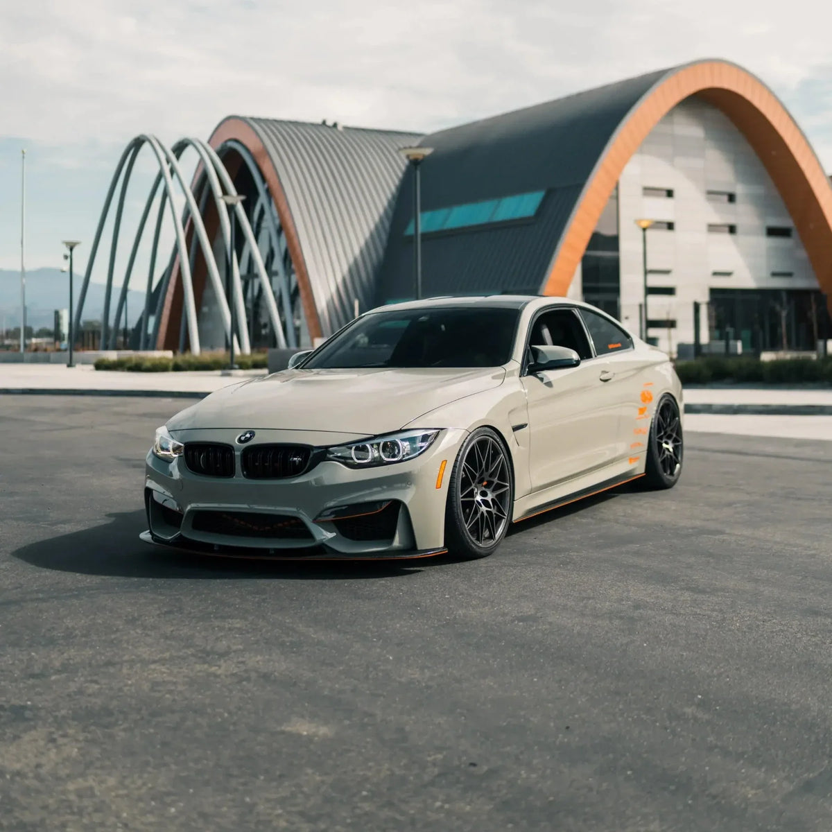 Gray BMW F82 M4 in front of a modern building, angled front view, with carbon front lip (3D Style)