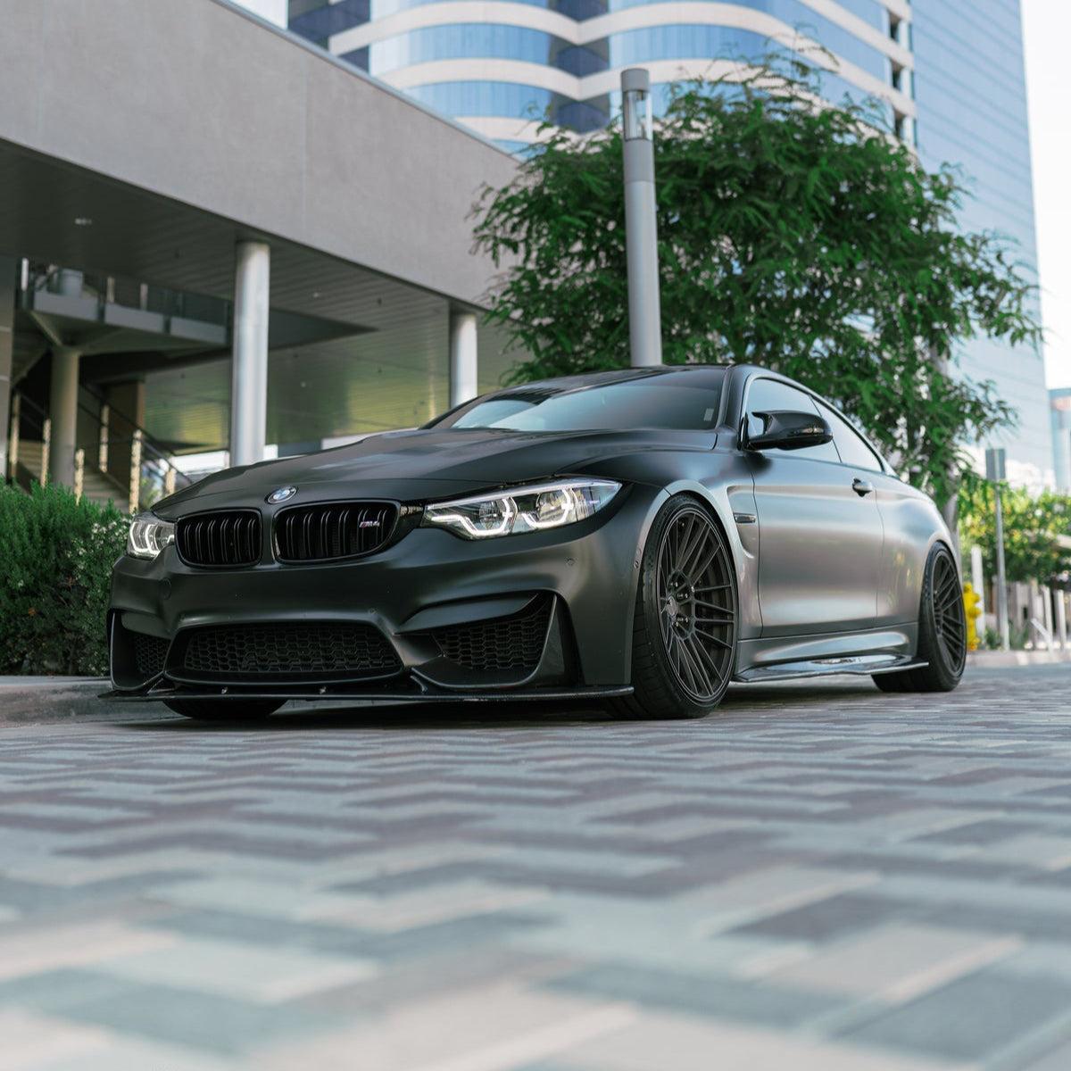 Matte black BMW F82 M4 from a low angle, angled front, with carbon front lip (3D Style)