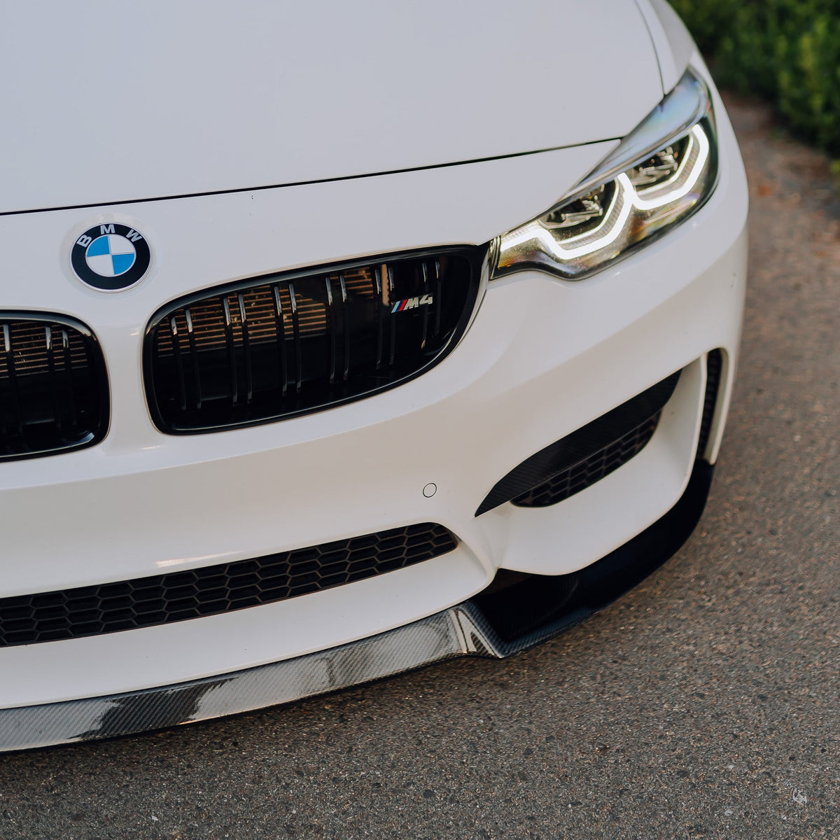 White BMW F82 M4 front corner close-up, with carbon front lip (CS Style)
