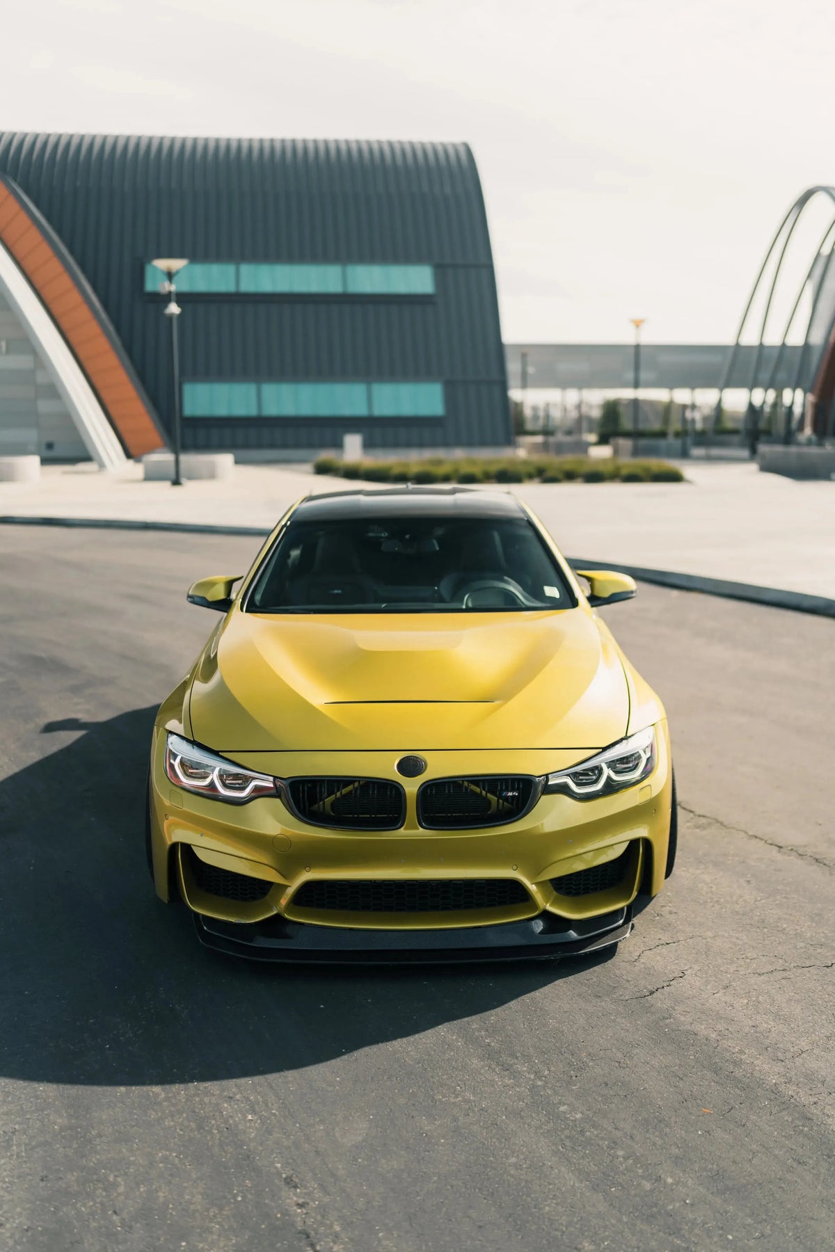 Yellow BMW F82 M4 head-on, with 2-piece carbon front lip (GTS Style)