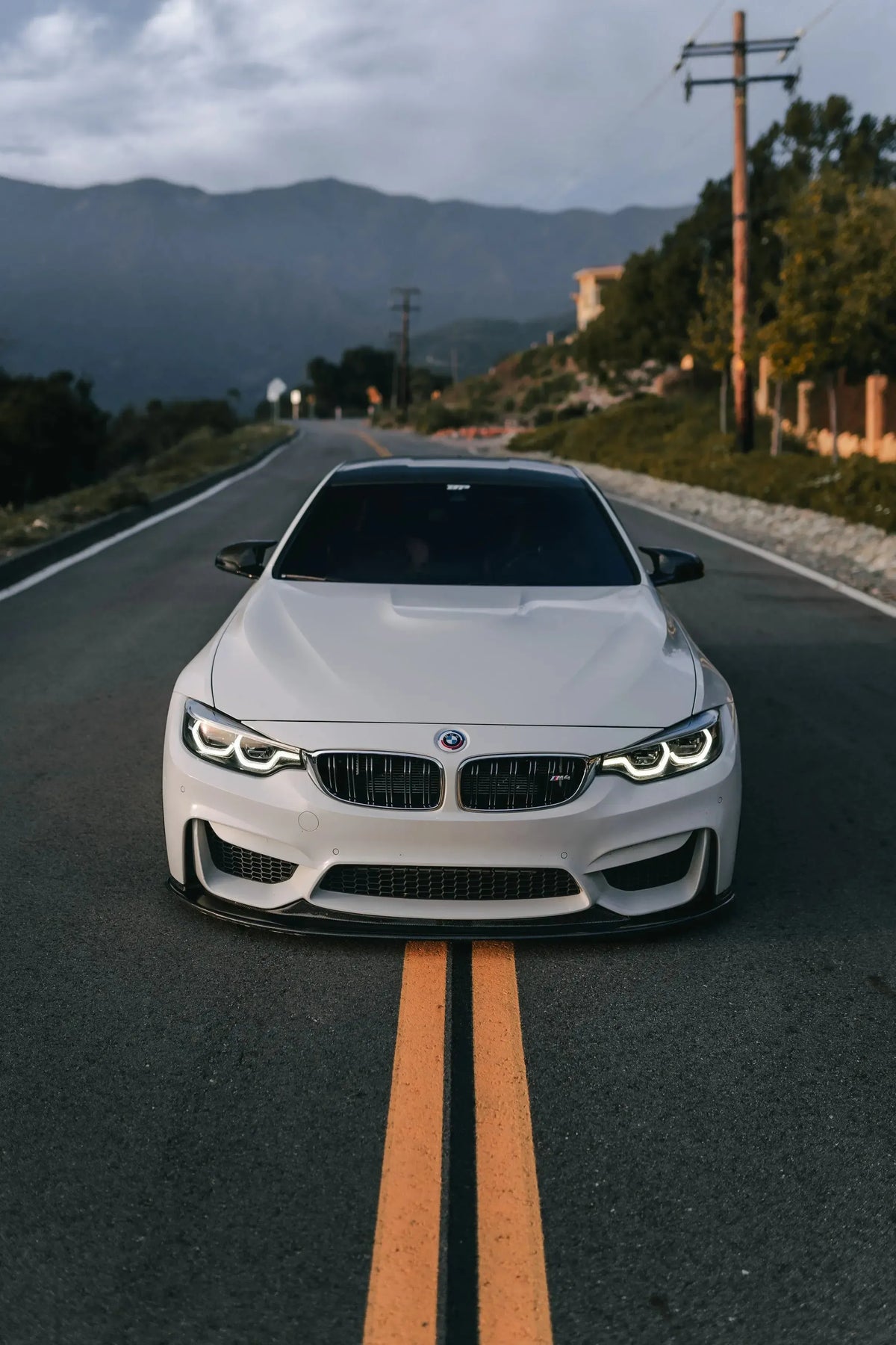 White BMW F82 M4 head-on on the road, with carbon fiber front lip (K Style)