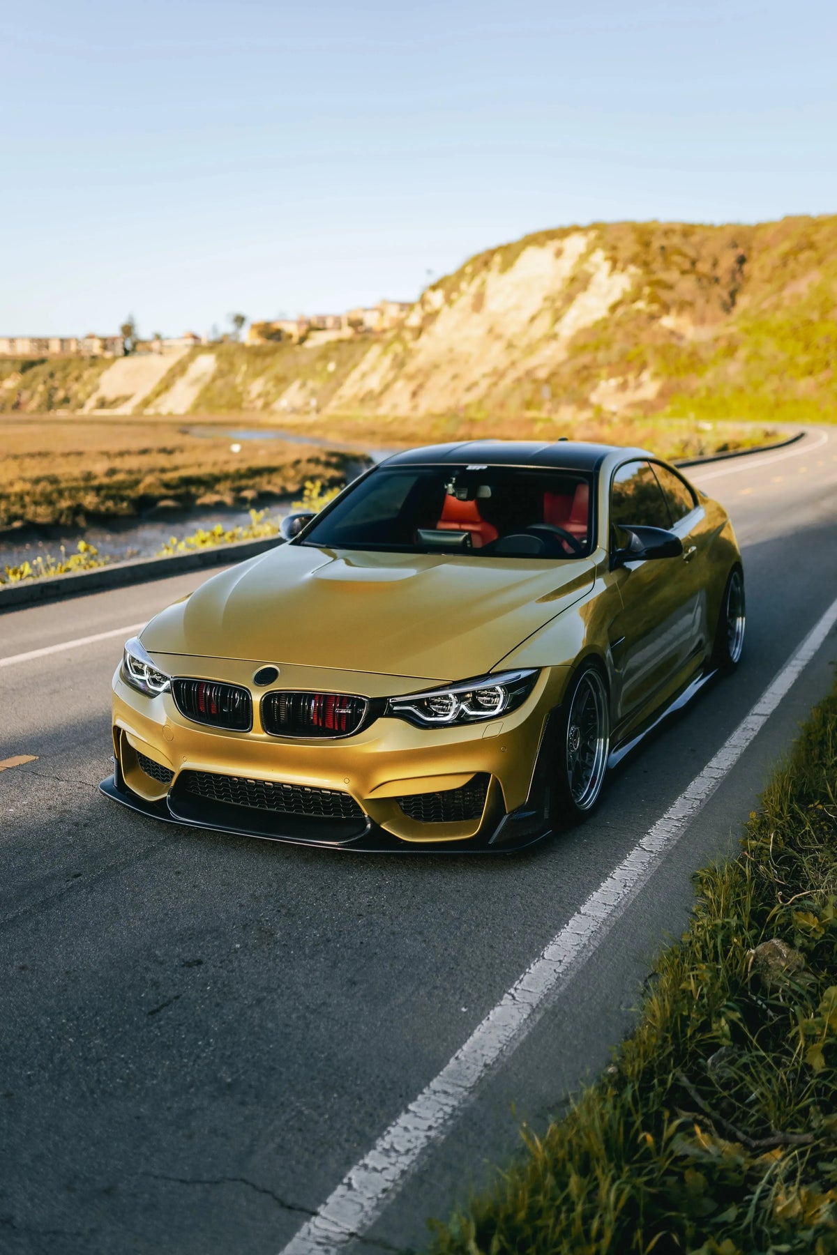 Carbon fiber front lip (Laptor Style) on a yellow BMW F82 M4, on a coastal road