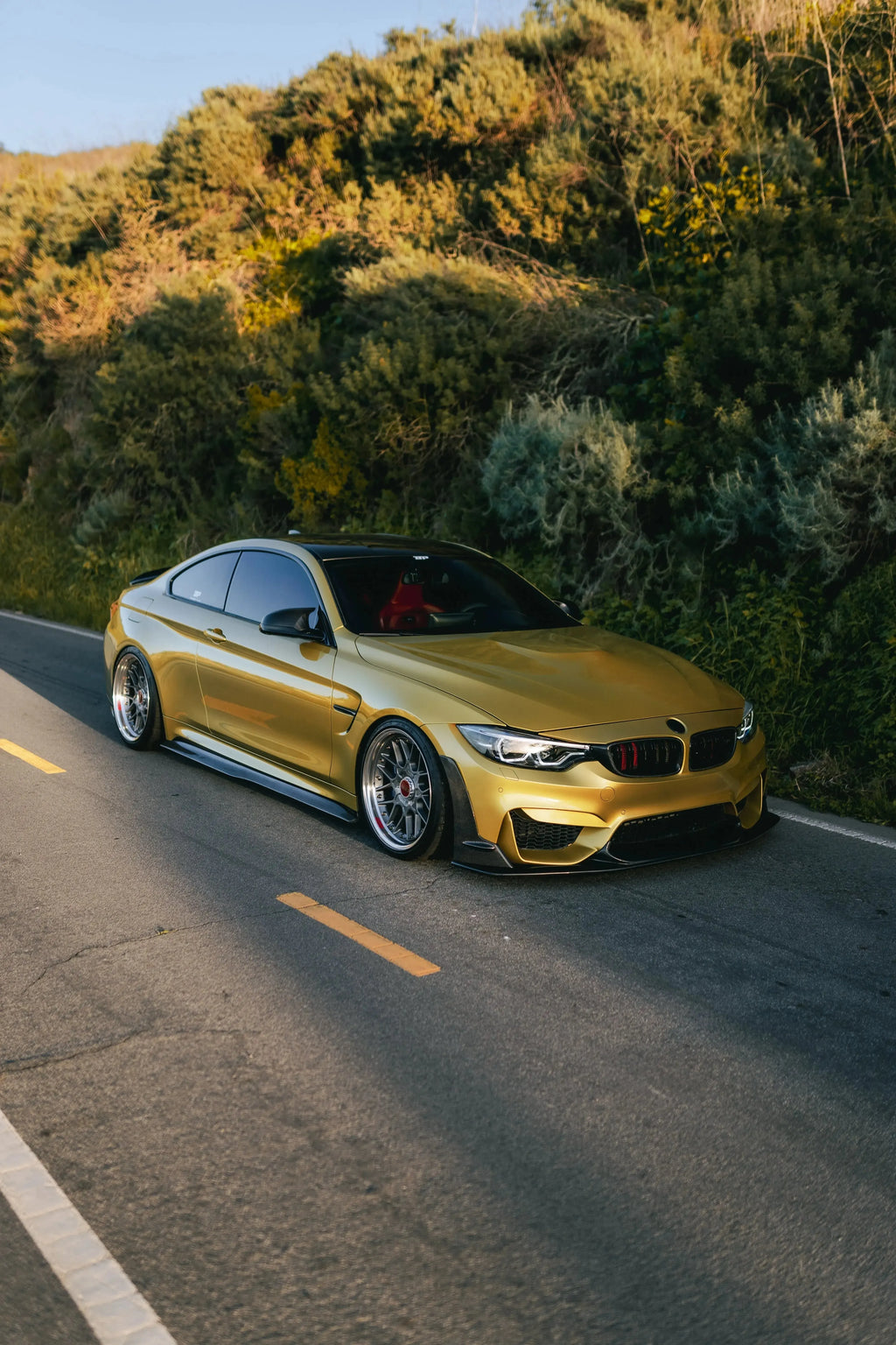 Yellow BMW F82 M4 in half profile on the road, fitted carbon front lip (Laptor Style)
