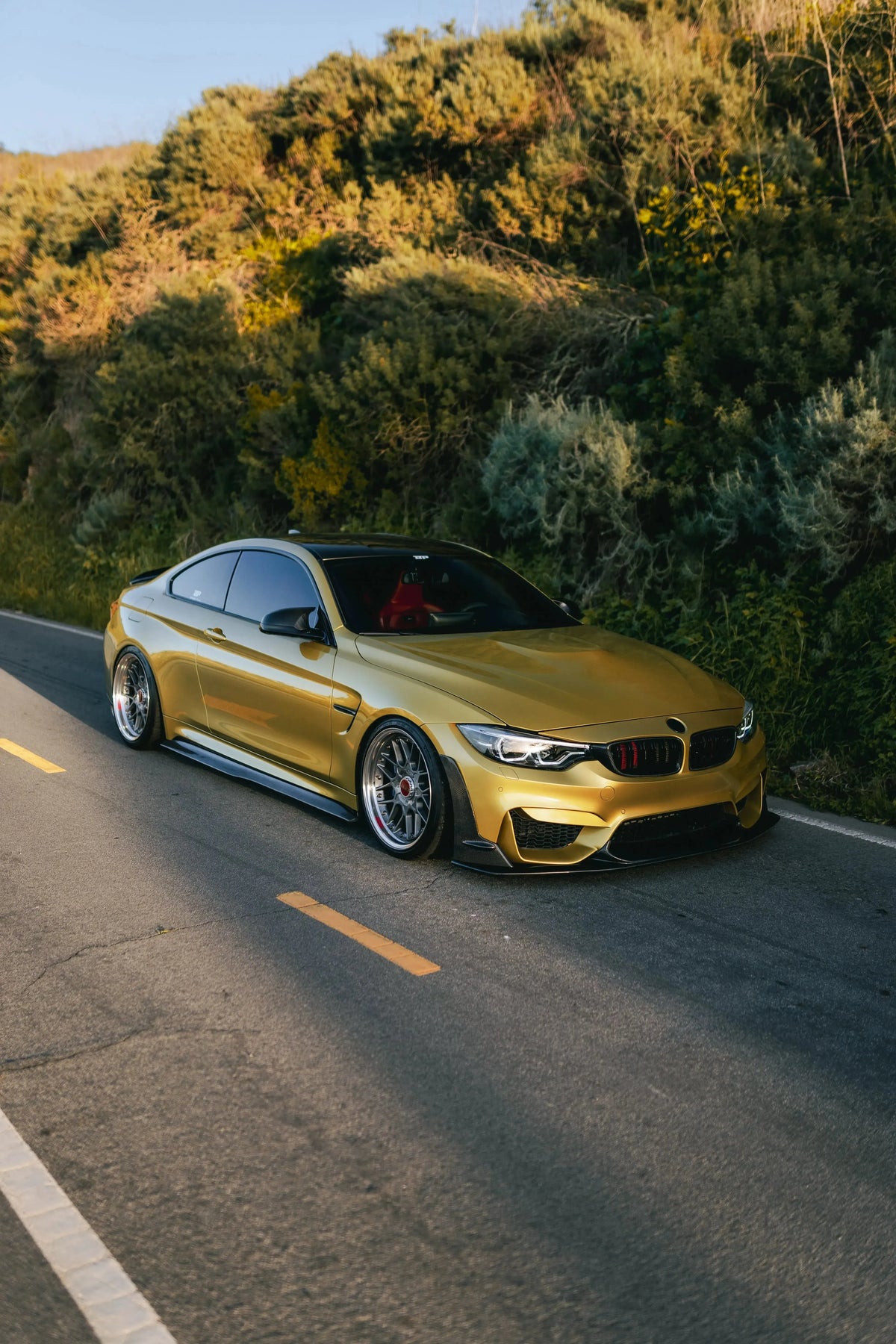 Yellow BMW F82 M4 in half profile on the road, fitted carbon front lip (Laptor Style)