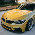 Carbon fiber front lip (MP Style) on the front of a yellow BMW F82 M4, three-quarter front view