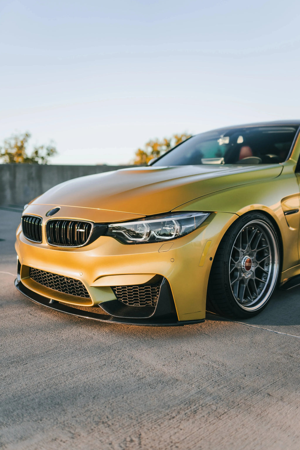 Yellow BMW F82 M4 from a low, angled front view, with carbon front corner splitters (MP Style)