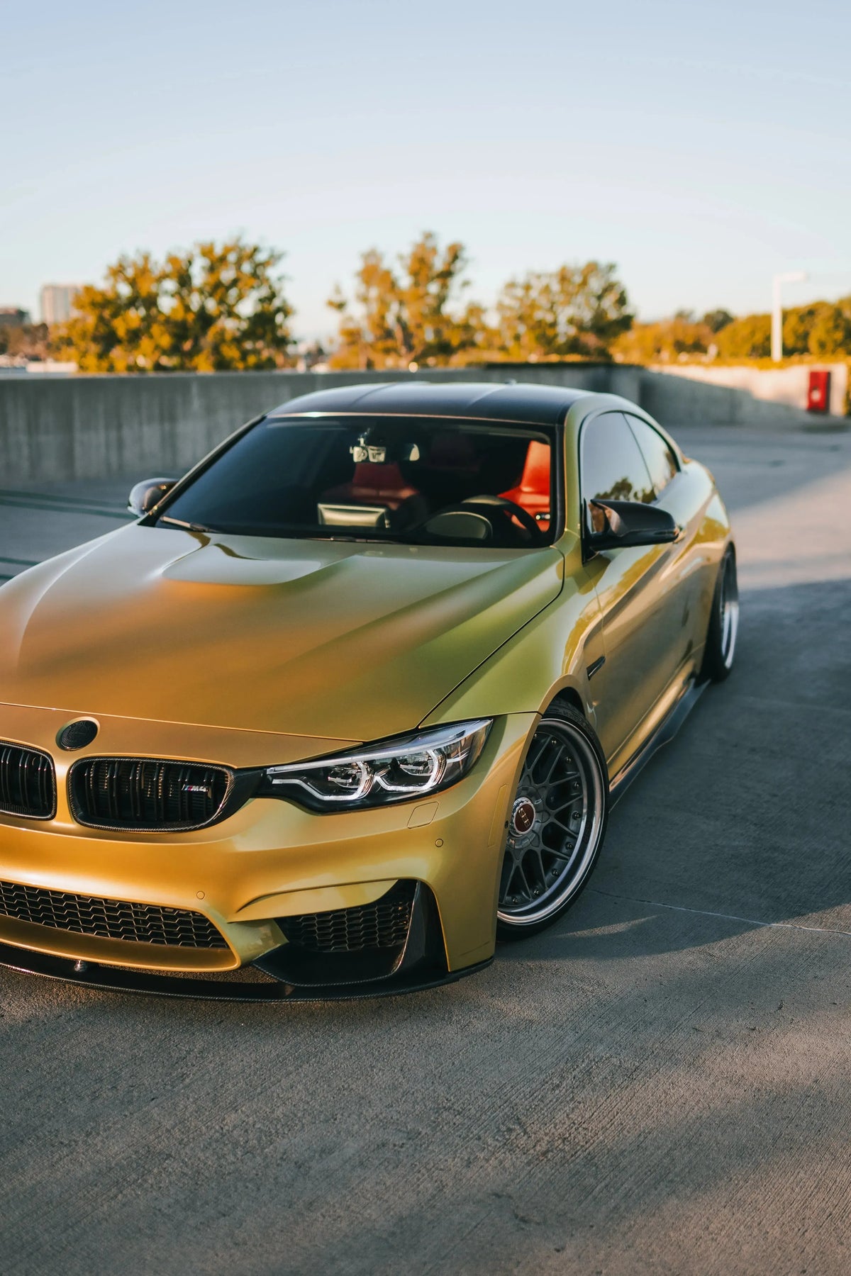 Carbon fiber front corner splitters (MP Style) on a yellow BMW F82 M4 in a parking garage, angled front view