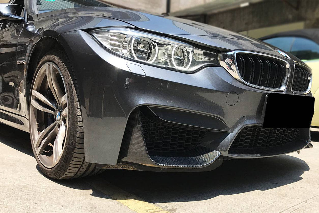 Gray BMW M3/M4 front bumper corner close-up, with carbon corner splitter (MP Style)
