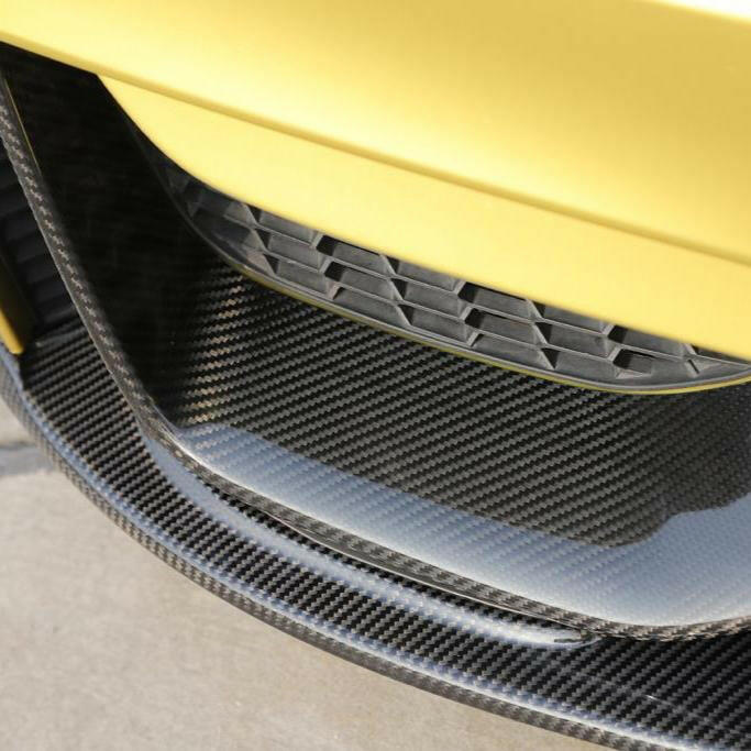 Carbon splitter weave close-up below the bumper air intake of a yellow BMW F82 M4 (Performance Style)