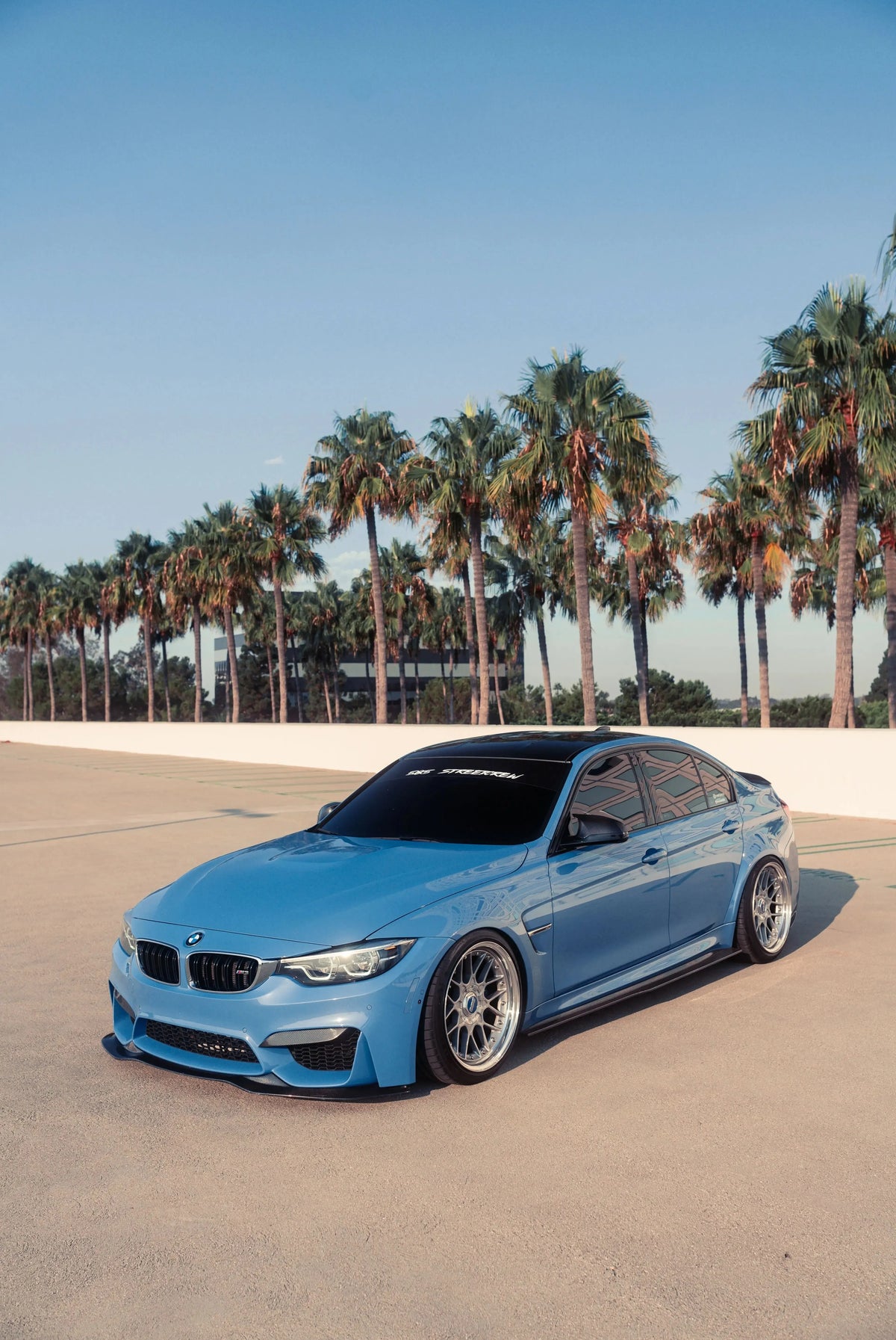 Carbon fiber front lip (PSM Style) on a blue BMW F80 M3 sedan, three-quarter front view