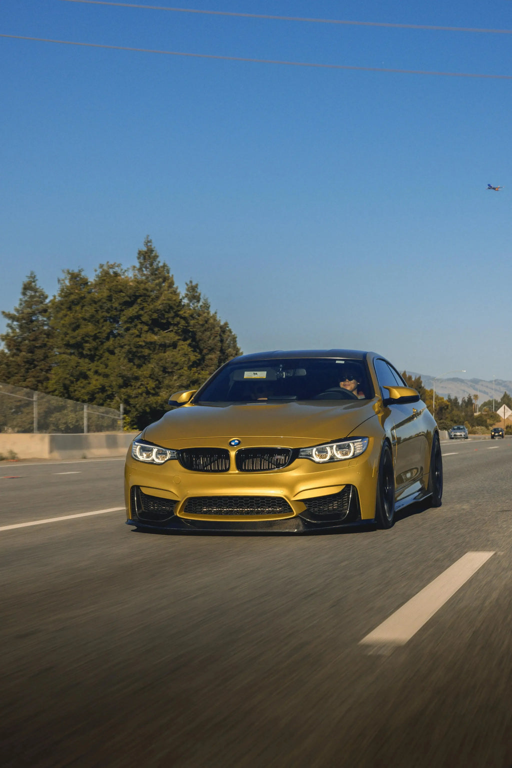 Yellow BMW F82 M4 driving on the road, from the front, with carbon fiber front lip (RSC Style)