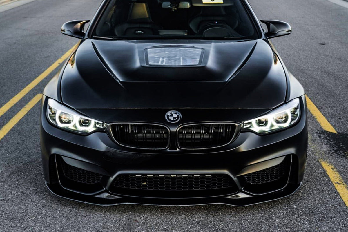 Black BMW F82 M4 head-on, with glass-window hood and carbon front lip (SM Style)