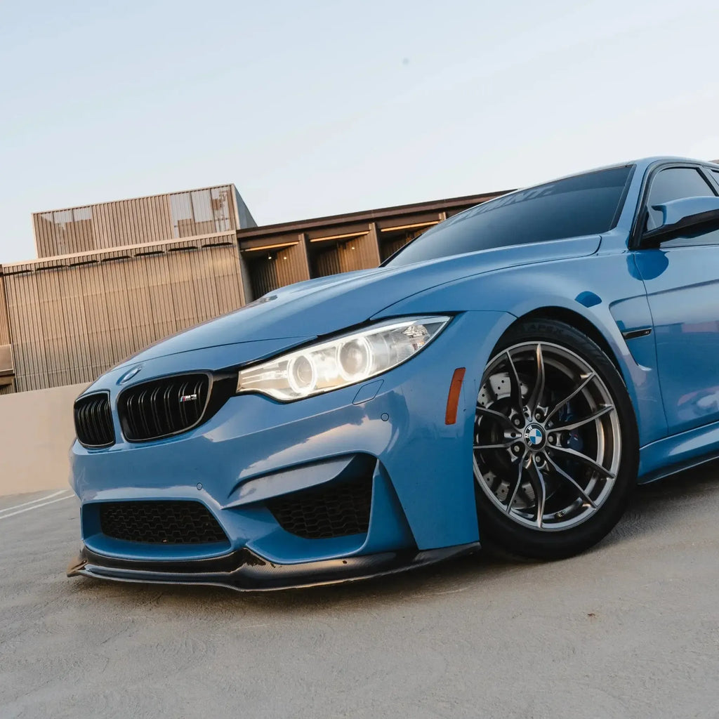 Blue BMW M3/M4 from a low, angled front view, fitted carbon front lip (V Style)