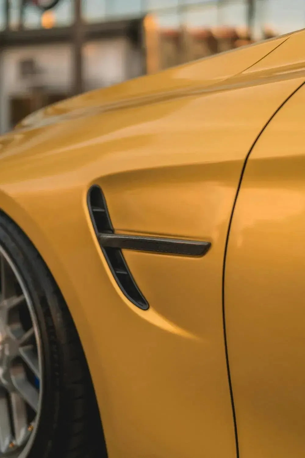 Carbon fender vent trim on the front fender, close-up on a yellow BMW F82 M4