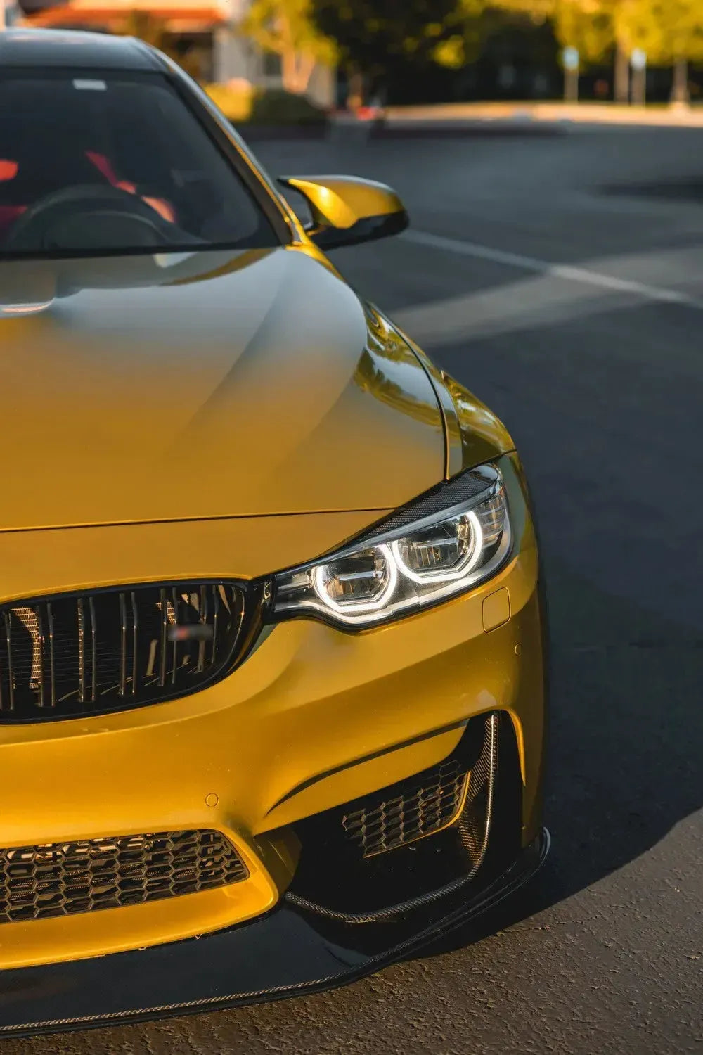 Carbon fiber szemöldök pár a fényszórókon, sárga BMW F82 M4 elölről 3/4-es nézetben