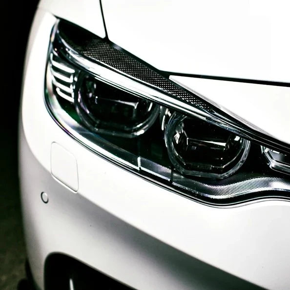 Beszerelt carbon fiber szemöldök fehér BMW F82 M4 / F32 fényszóróján, közelről