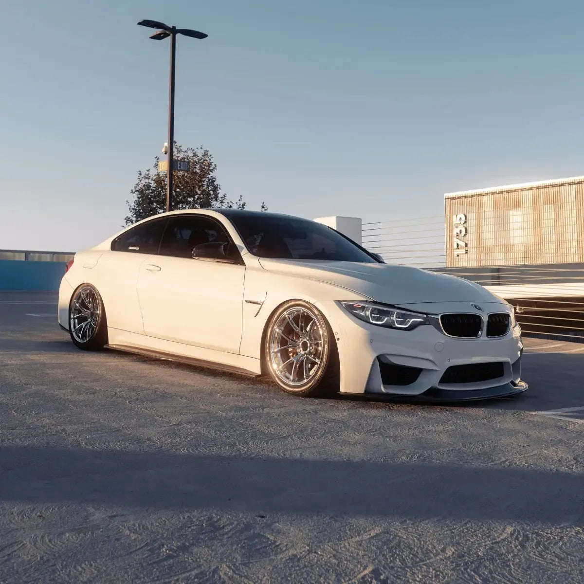 Full LED headlight pair on a white BMW F82 M4 on a rooftop, three-quarter front view (LCI Ikon Style)