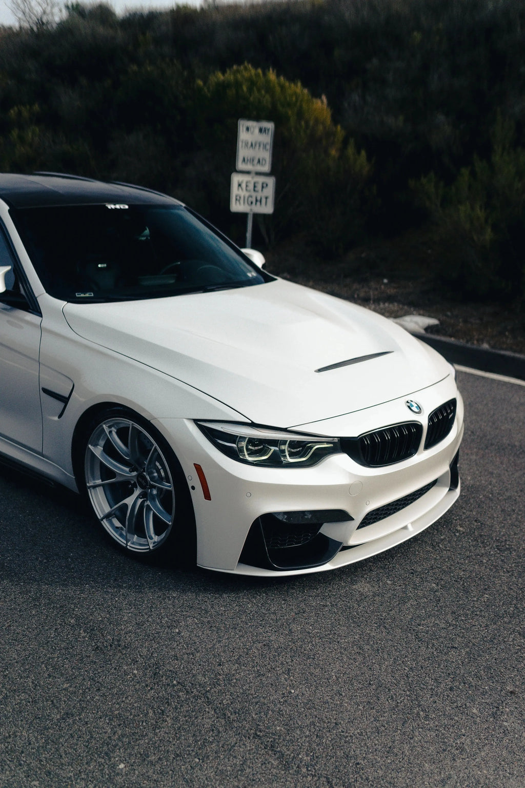 Fehér BMW F80 M3 közeli, ferde elölnézetben, felszerelt alumínium motorháztetővel (GTS Style)