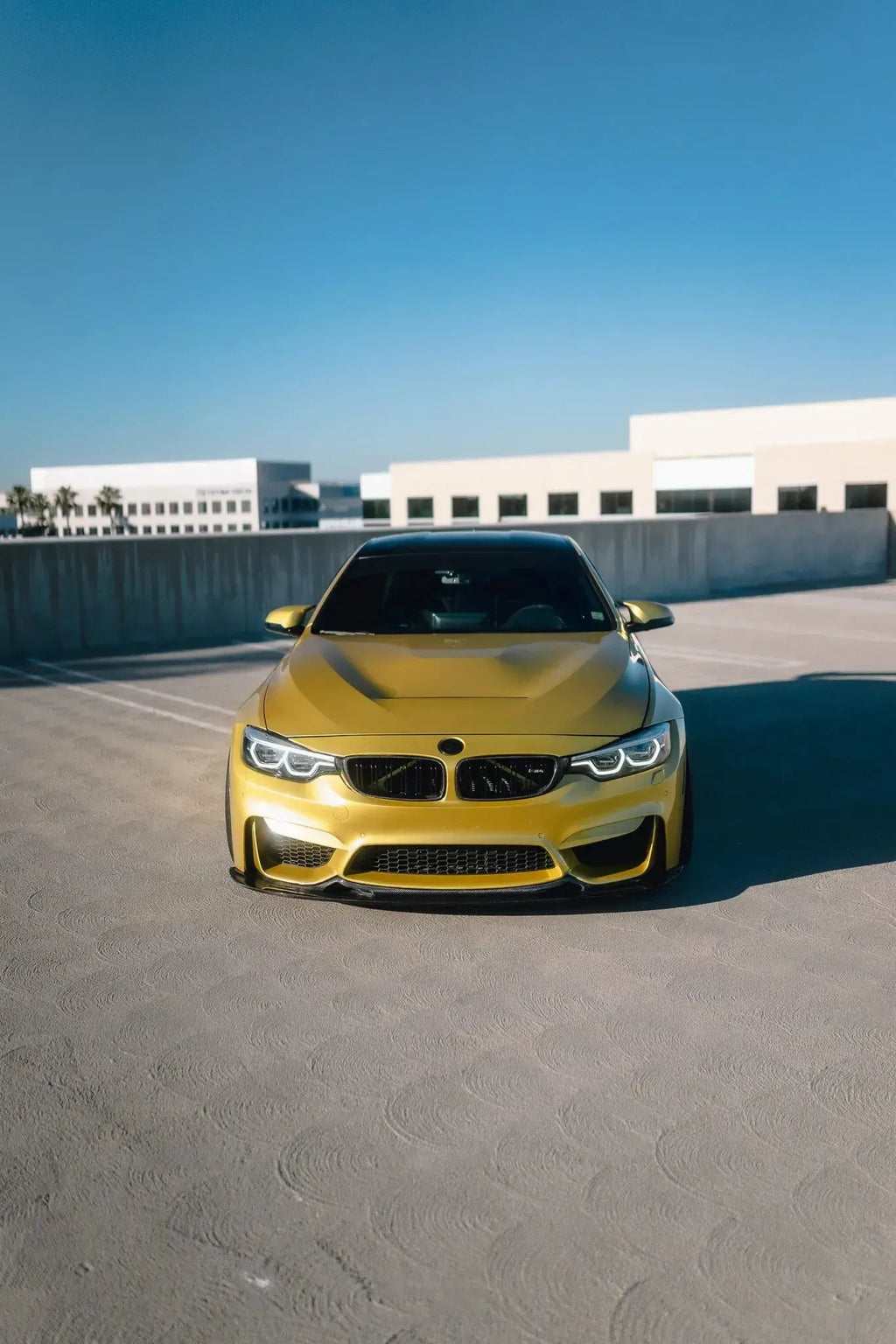 Sárga BMW F82 M4 egyenesen elölről a parkolószinten, alumínium motorháztetővel (GTS Style)