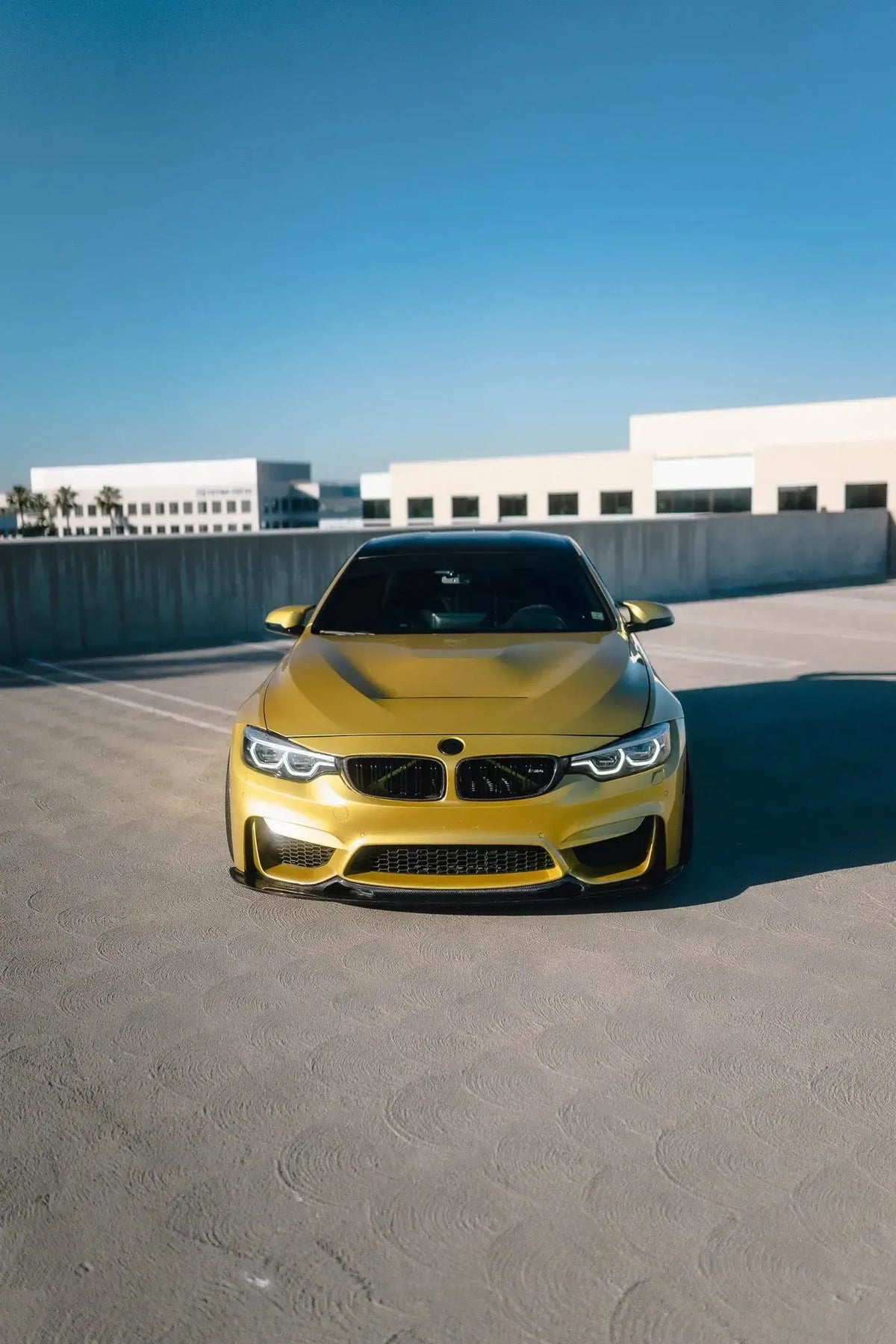 Sárga BMW F82 M4 egyenesen elölről a parkolószinten, alumínium motorháztetővel (GTS Style)