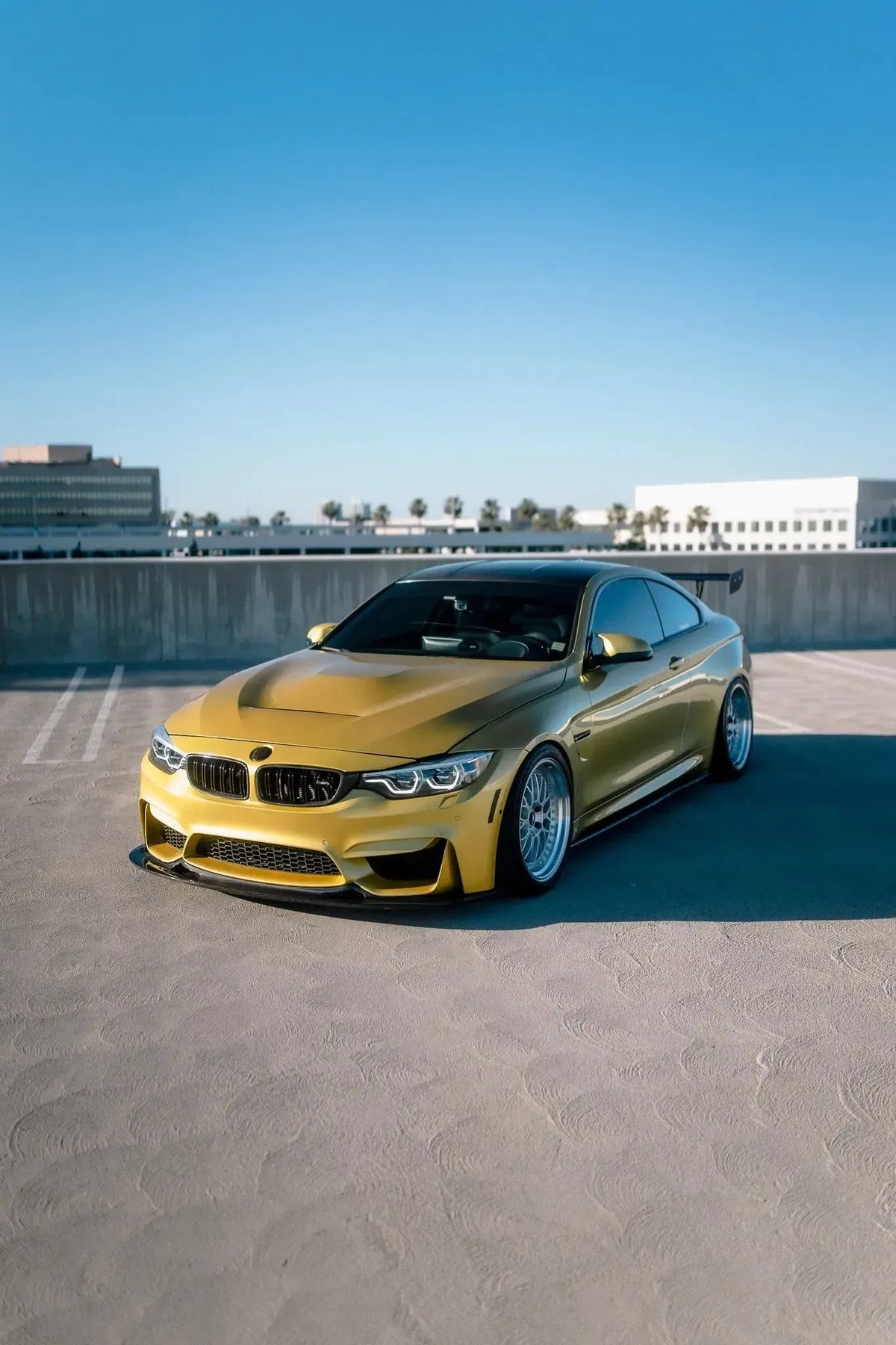 Sárga BMW F82 M4 ferde elölnézetben a parkolószinten, felszerelt alumínium motorháztetővel (GTS Style)