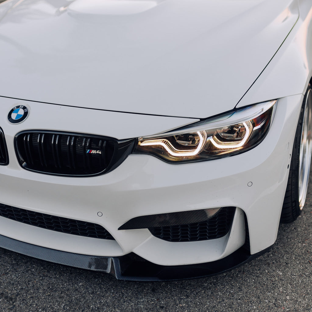 Fehér BMW F82 M4 első sarka közelről, fényes fekete dupla rácsos vesével