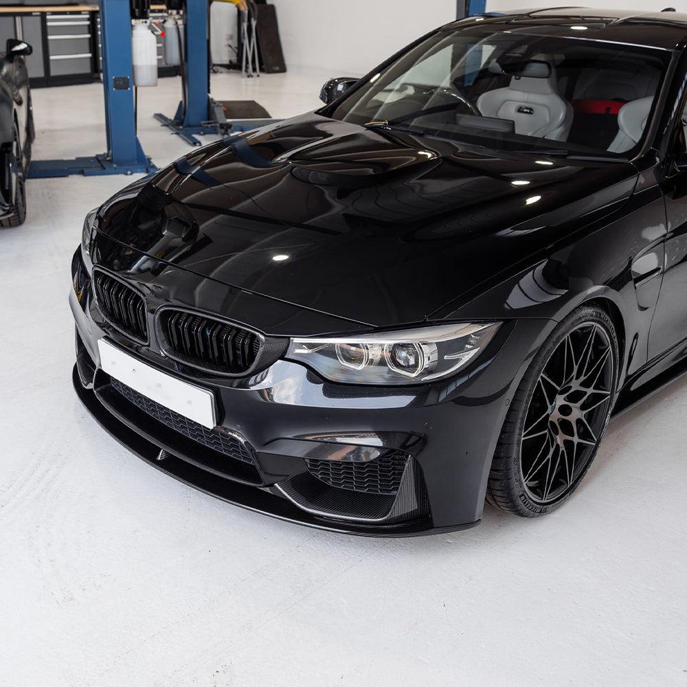 Fekete BMW F82 M4 elölről ferdén a műhelyben, felszerelt carbon vesékkel (PM Style)
