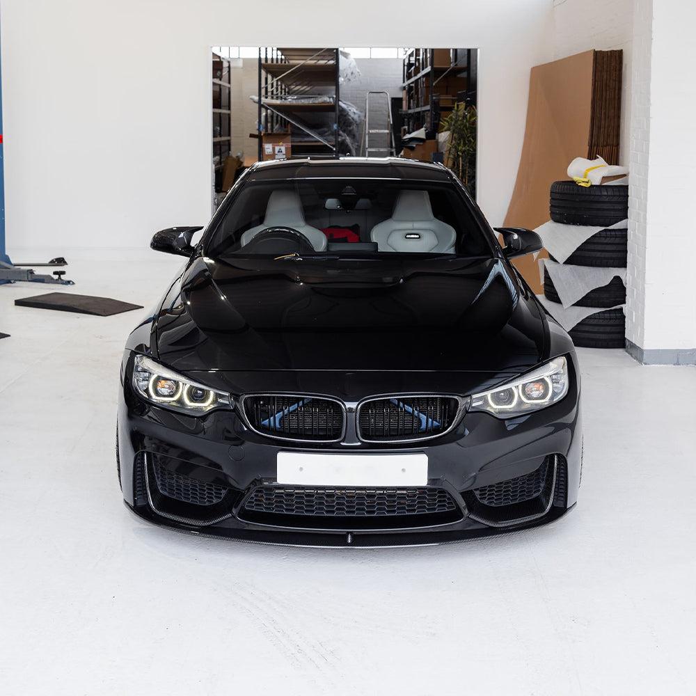 Fekete BMW F82 M4 elölnézetből a műhelyben, carbon vesékkel szerelve (PM Style)
