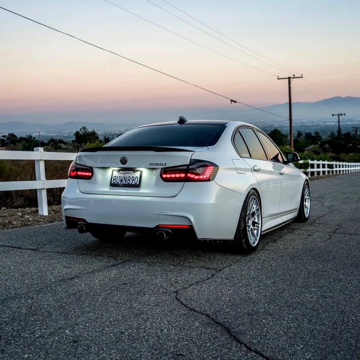 Smoked LED tail lights lit on a white BMW F30 at dusk, three-quarter rear view (GTS Style)