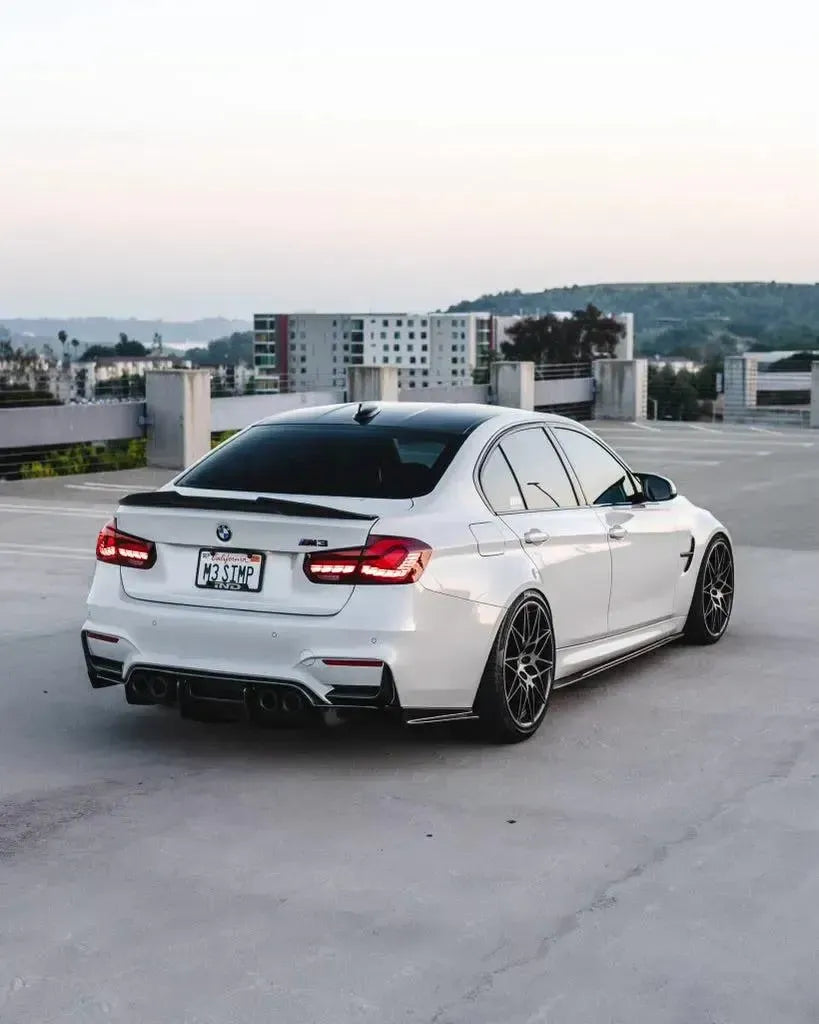 White BMW F80 M3 in a parking garage, red sequential OLED tail lights, three-quarter view (GTS Style)