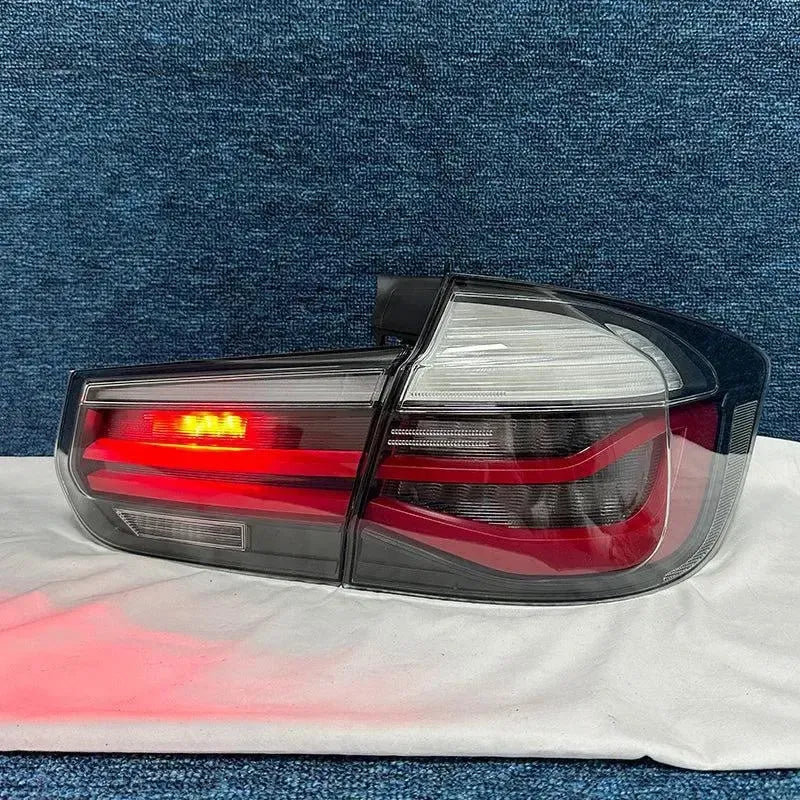 Smoked sequential tail light set on a table, one unit illuminated (LCI Style) – BMW F80 M3 / F30