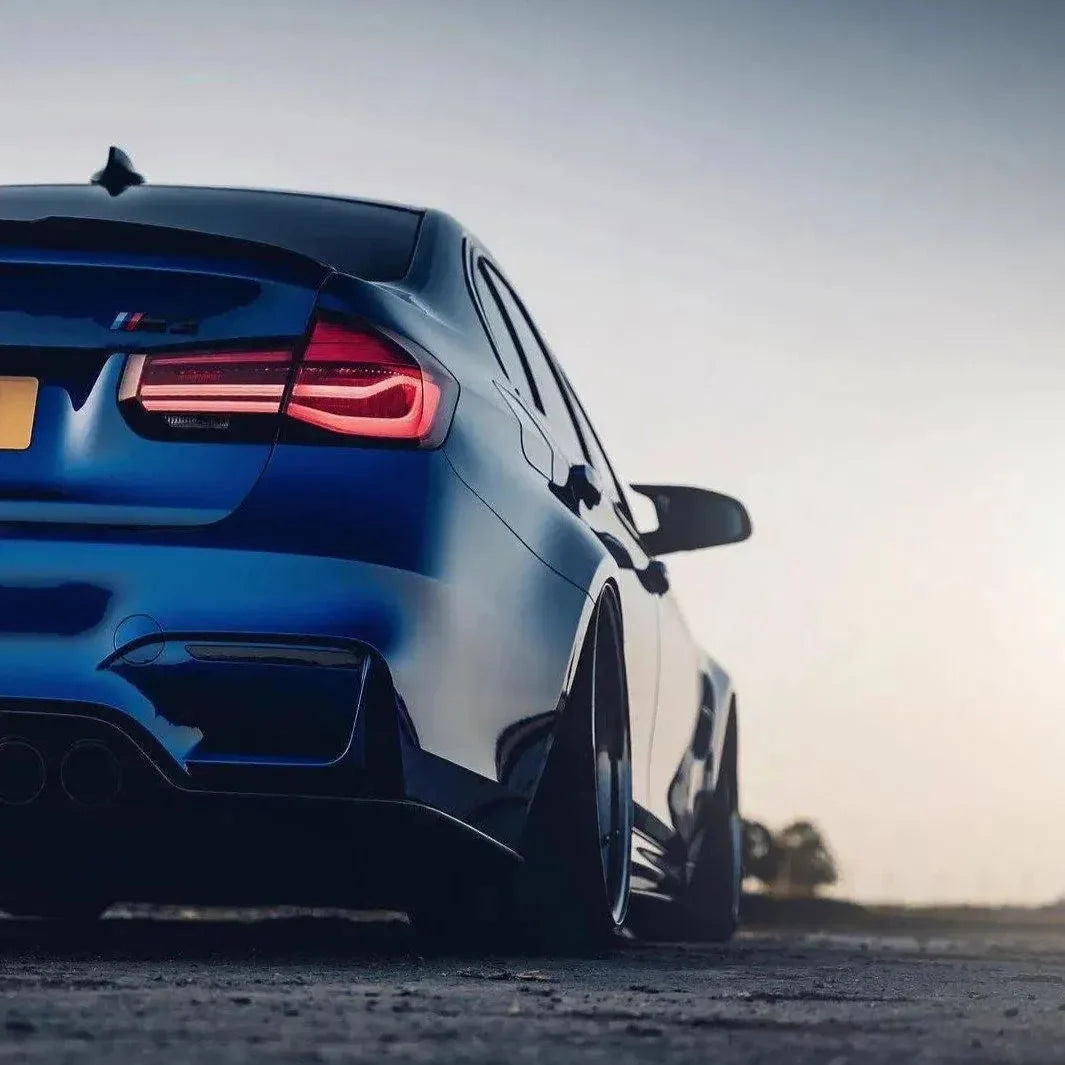 Blue BMW F80 M3 from a low rear three-quarter angle, illuminated red sequential tail lights (LCI Style)