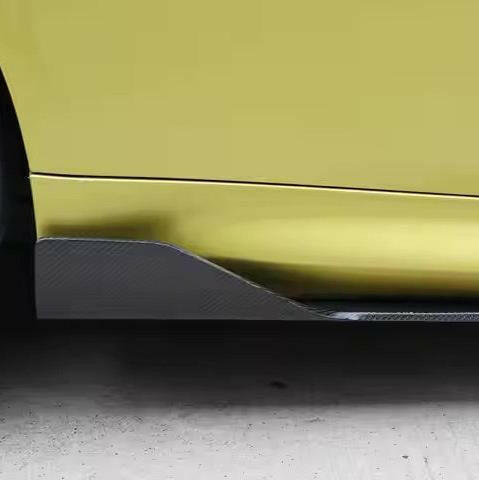 Carbon side skirt fin fitted to the rear end of the side sill of a yellow BMW M4