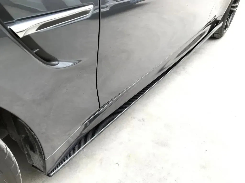 Carbon side skirt of a dark gray BMW M4 close-up, viewed from the front wheel (VRS Style)