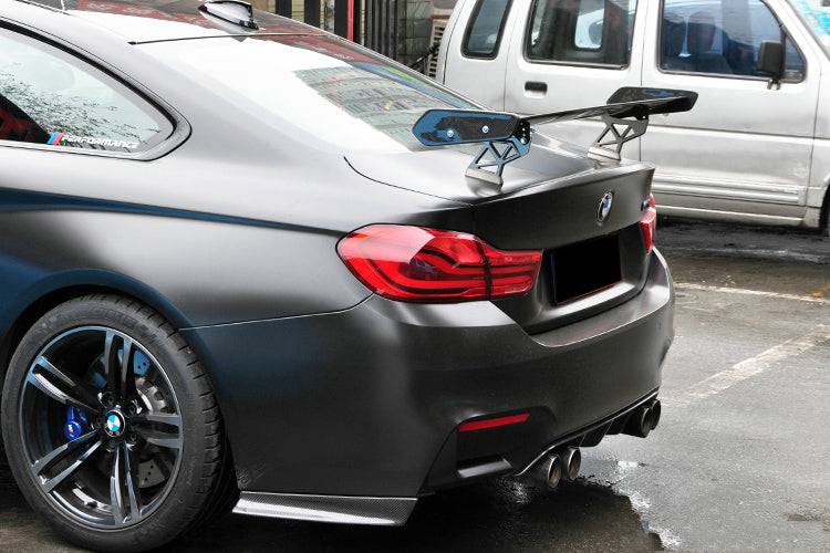 Matte gray BMW M4 in rear three-quarter view, with swan-neck carbon rear wing (GTS Style)