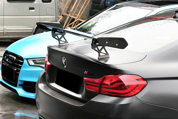 Matte gray BMW M4 trunk close-up, with carbon wing with end plates on swan-neck mounts (GTS Style)