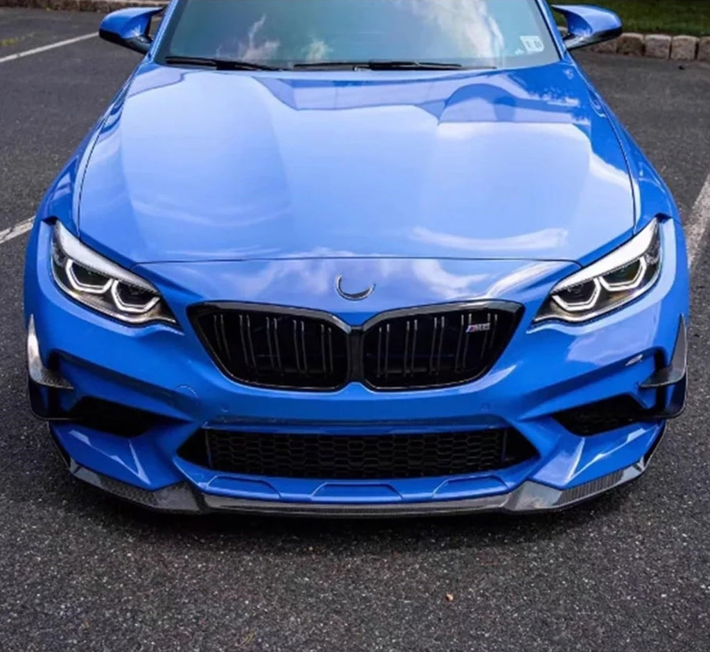 Front view of a blue BMW F87 M2 with carbon fiber front canards and carbon front lip
